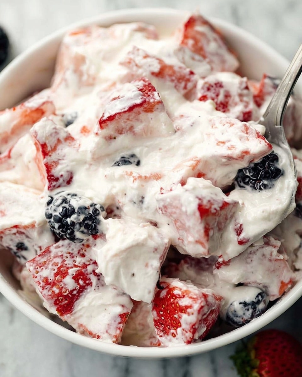 A close-up of a white bowl filled with a mixed fruit salad layered with white creamy cottage cheese. The salad contains large pieces of light pink strawberry slices and small dark blackberries and blueberries scattered throughout. The cottage cheese has a slightly lumpy texture, covering and blending the fruit pieces. Around the bowl, there are cut strawberries and a few blueberries and blackberries resting on a white marbled surface. The scene is bright and fresh, showing a simple, healthy fruit and cheese mix photo taken with an iphone --ar 4:5 --v 7