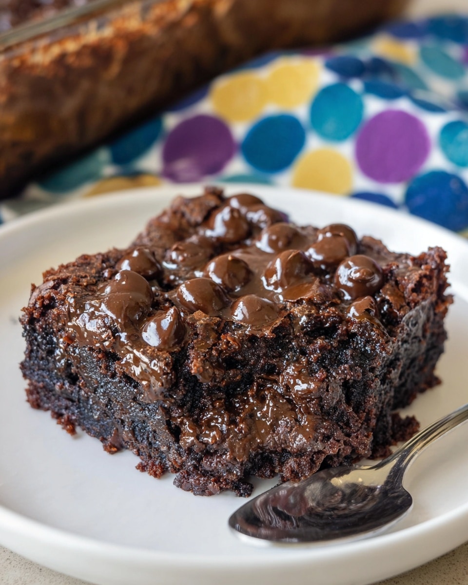A square piece of rich chocolate brownie sits on a white plate, its surface rough and filled with many shiny and smooth chocolate chips melted partially into the top and sides. The brownie has three visible layers: a thick, dark brown, moist cake base with a fudgy texture, a middle layer of melted chocolate chips creating glossy patches, and a top layer covered densely with whole and melted chocolate chips, giving it a lumpy and gooey look. The background includes a blurred wood log and a colorful fabric with blue, yellow, and purple circular patterns, and a silver spoon is partly visible on the plate. Photo taken with an iphone --ar 4:5 --v 7