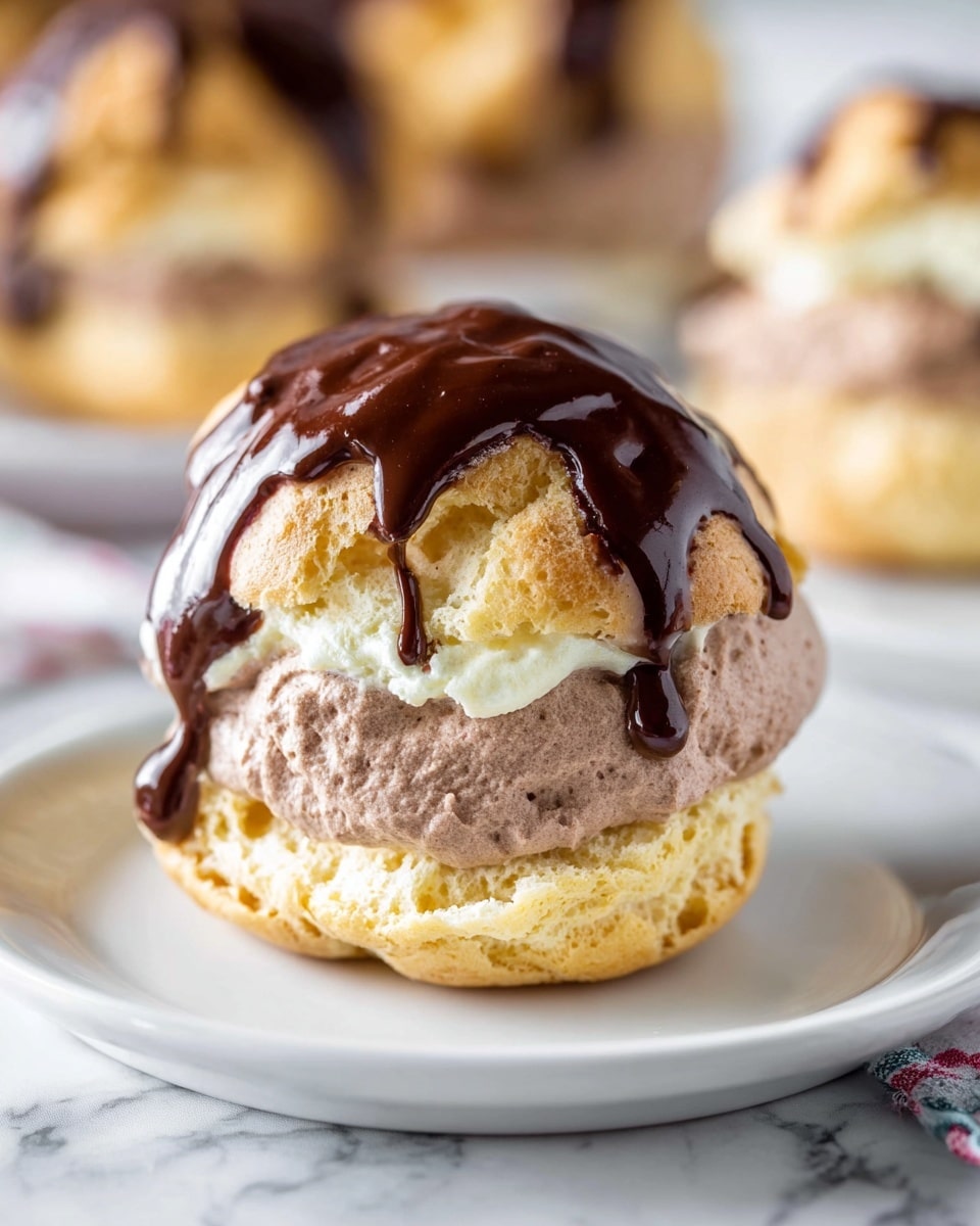 The image shows a cream puff dessert placed on a white plate with a white marbled surface beneath. The dessert has three visible layers: the bottom and top layers are light golden-brown, airy pastry shells with a slightly rough texture. Sandwiched between them is a thick, fluffy layer of pale brown chocolate cream. On top of the puff is a generous drizzle of shiny, dark chocolate sauce that flows down the sides, adding a rich glossy contrast to the soft pastry. The background is softly blurred, highlighting the detailed texture of the cream puff in focus. photo taken with an iphone --ar 4:5 --v 7