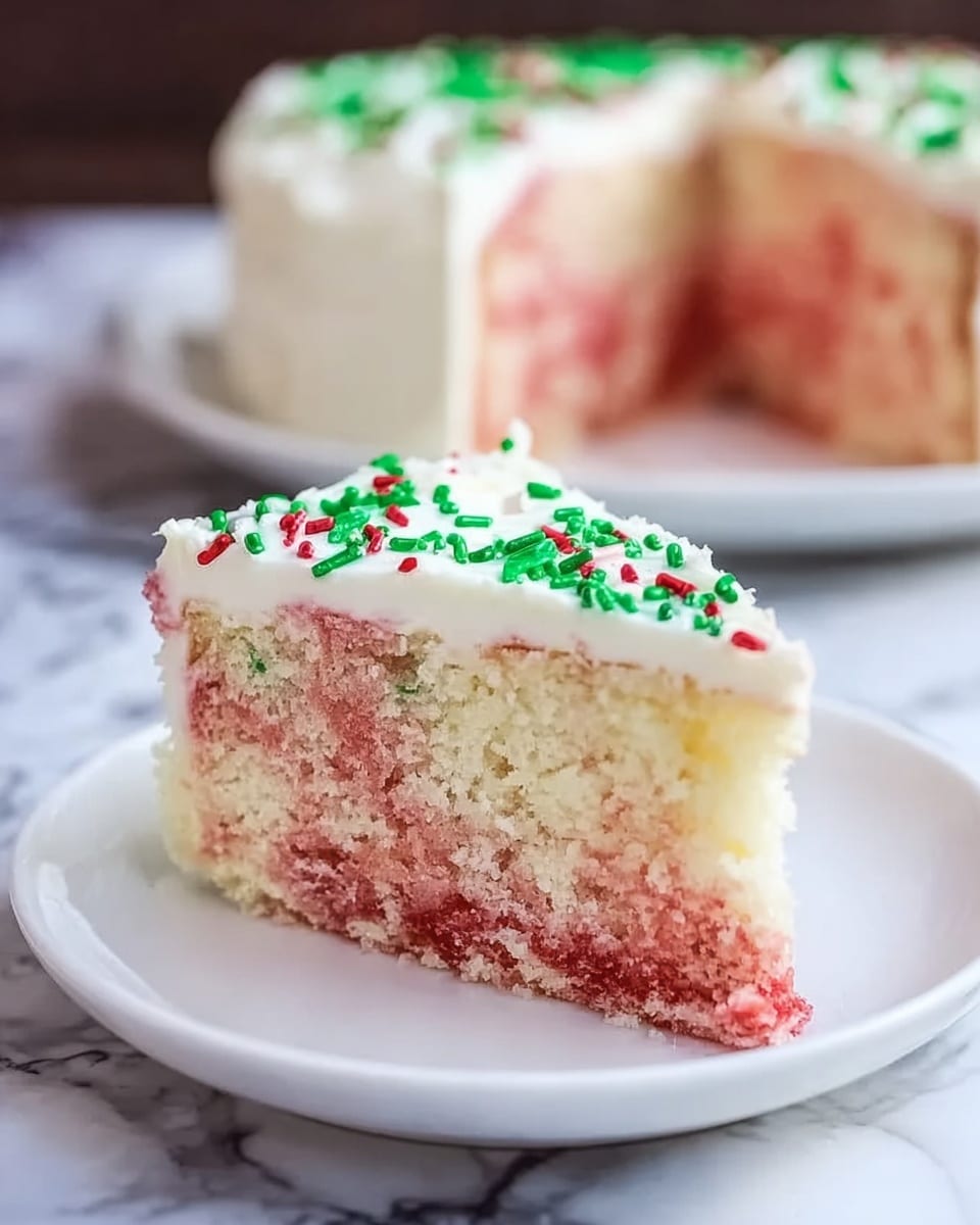 A slice of cake on a white plate with a white marbled surface below, featuring two main layers: the bottom layer is a mix of light pink and white, showing a moist texture with marbled swirls, while the top layer is a thick, smooth white frosting spread evenly, decorated with small green and red sprinkles scattered across the surface. In the background, the full cake is visible, with the same frosting and decorations on top, slightly out of focus. photo taken with an iphone --ar 4:5 --v 7