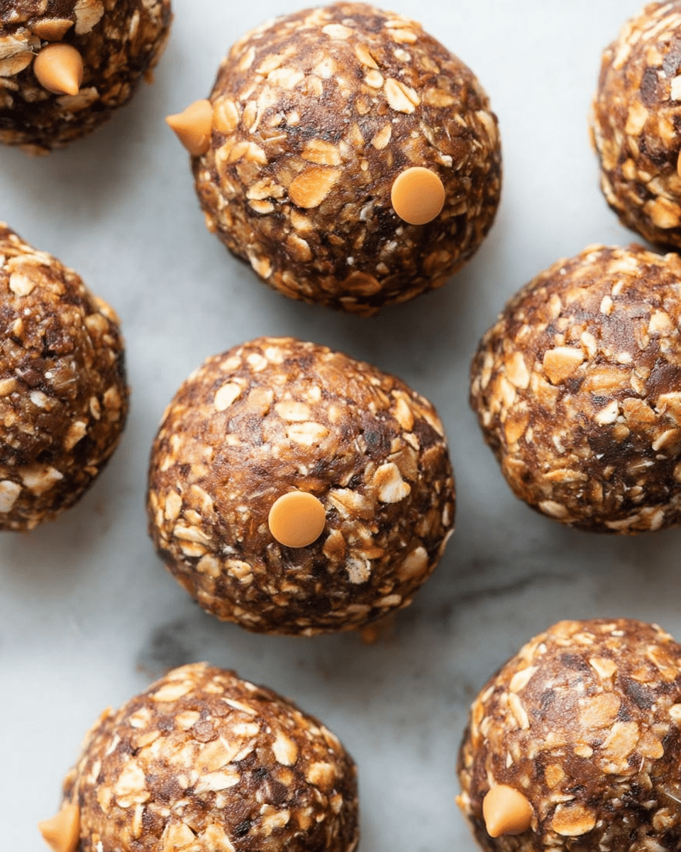 The image shows several round energy balls closely placed together on a white marbled surface. Each ball has a rough texture with three main layers visible: a base made of small rolled oats mixed tightly with a dark brown ingredient, likely cocoa or cinnamon, creating a speckled texture; scattered throughout are smooth, round butterscotch-colored chips adding an orange-tan color contrast; and the whole surface has a natural, irregular pattern with oats sticking out in places. The balls appear dense and moist, with the oats giving a flaky, slightly rough look. photo taken with an iphone --ar 4:5 --v 7