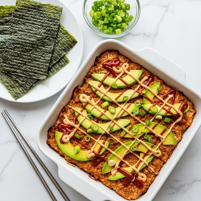 A square white baking pan holds a dish with one main layer of browned food topped with thin slices of light green avocado arranged across the surface. Over the avocado, there are crisscrossing lines of reddish-brown sauce and creamy beige sauce, creating a grid pattern. Bright green chopped scallions are scattered on top, adding fresh color. To the left, a white plate holds several dark green sheets of seaweed, and to the upper right, a small clear bowl is filled with more chopped scallions. The pan is placed on a white marbled surface, with metal chopsticks resting beside it. Photo taken with an iphone --ar 4:5 --v 7