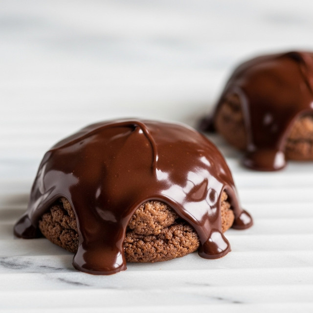 The image shows two chocolate-covered cookies on a white marbled textured surface with raised horizontal lines. Each cookie is thick with a dark brown, glossy chocolate layer that covers the top and drips down the sides, pooling slightly around the base in a smooth, shiny layer. The chocolate has a rich, melted look, with small folds and ripples on the surface. The cookies beneath appear soft and slightly rough, contrasting with the smooth chocolate. The focus is on the front cookie, with the second cookie blurred in the background. photo taken with an iphone --ar 4:5 --v 7