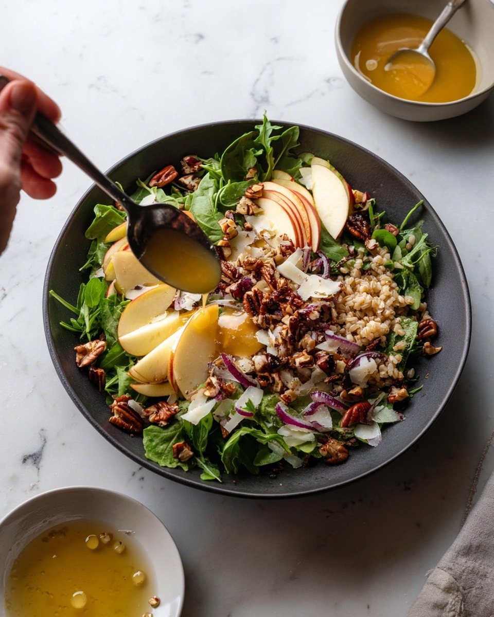 A dark bowl sits on a white marbled surface, filled with a layered salad starting with a base of green leafy arugula mixed with tan cooked grains. On top, there are thin pale yellow apple slices fanned out on one side, along with small red apple chunks scattered throughout. Shiny dark brown pecan pieces and thinly sliced light purple shallots are sprinkled over the salad. Thin, translucent white shavings of cheese add texture, and a woman's hand holding a spoon is drizzling golden honey sauce from above. Nearby, a white bowl contains more of the honey sauce, with a few drops spilled on the surface. Photo taken with an iphone --ar 4:5 --v 7