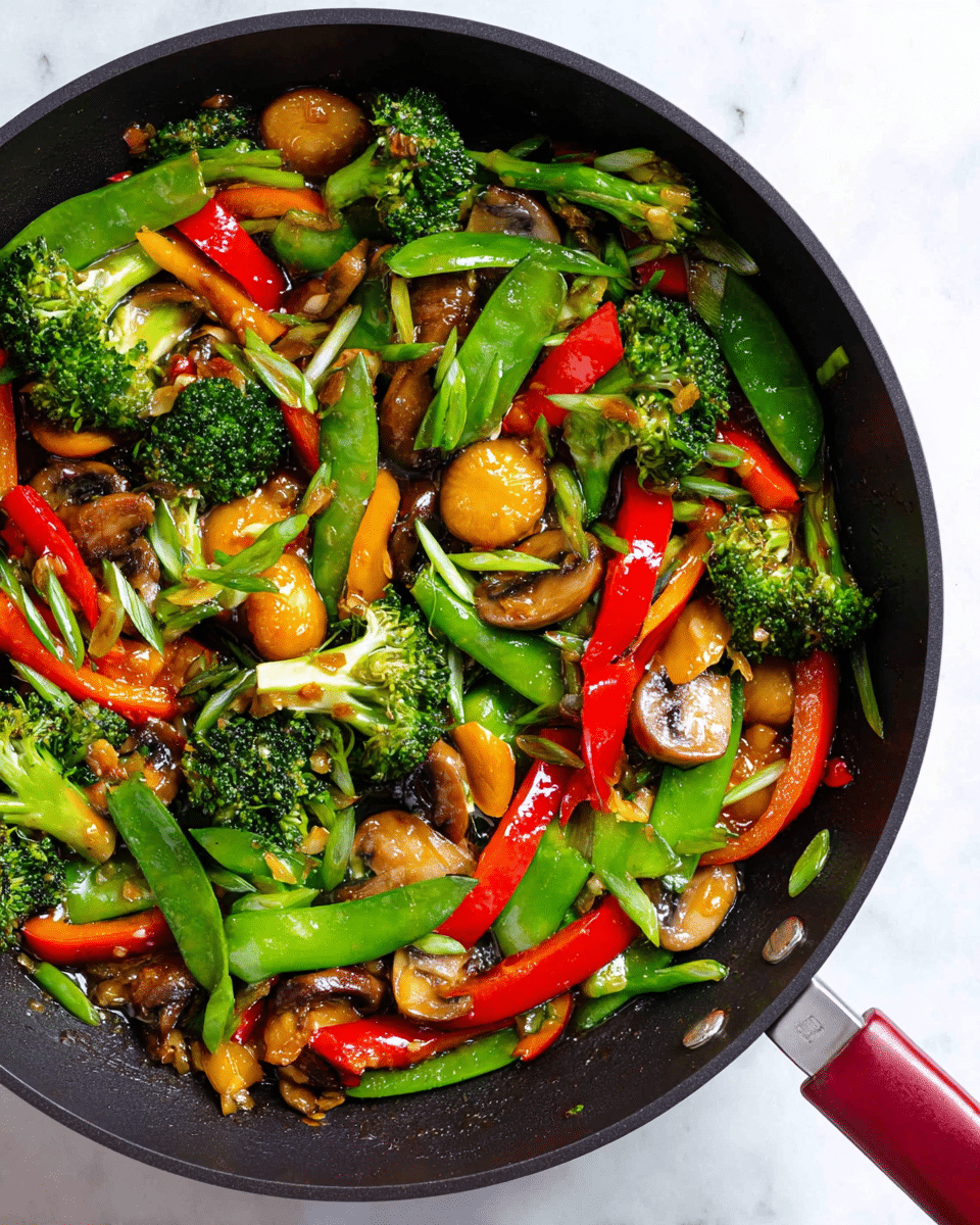 The image shows a close-up of a black pan filled with colorful stir-fried vegetables on a white marbled surface. The dish has several layers of vibrant vegetables: bright green broccoli florets, red bell pepper strips, shiny sugar snap peas, golden brown water chestnuts, and sliced brown mushrooms. The vegetables have a slightly glossy texture from a light sauce, and bits of garlic are scattered throughout. The pan handle with a red grip is partially visible on the right side. photo taken with an iphone --ar 4:5 --v 7