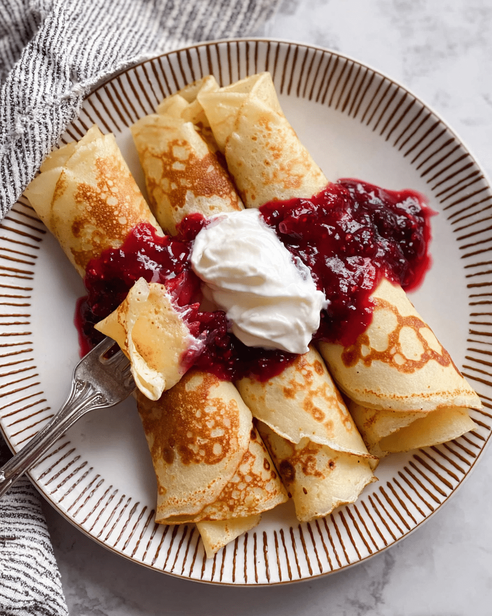 The image shows three rolled crepes arranged side by side on a white plate with brown striped edges. Each crepe has a light golden-brown color with some darker browned spots, showing a soft and slightly crispy texture. On top of the crepes, there is a thick layer of deep red berry sauce spread across the center, and a dollop of white whipped cream sits slightly off-center on the sauce. A silver fork is cutting into the closest crepe, lifting a small piece. The plate is set on a surface with a white marbled texture, and a striped cloth is partially visible beside it. Photo taken with an iphone --ar 4:5 --v 7