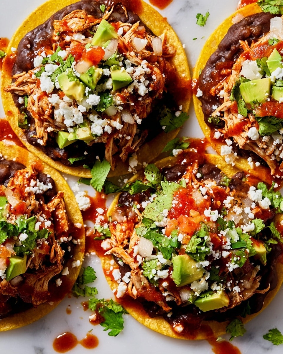 Three tostadas are shown on a bright white marbled surface, each with a yellow crispy corn shell base. On top of the shell is a thick layer of dark brown refried beans, spread evenly. Over the beans, there is shredded cooked chicken mixed with small diced red tomatoes and white onions. Small pieces of green avocado are scattered across the tostadas, along with fresh green cilantro leaves and crumbled white cheese. A reddish-brown salsa is drizzled over the toppings, creating a colorful contrast. Some bits of salsa and toppings are scattered around on the white marbled background. photo taken with an iphone --ar 4:5 --v 7