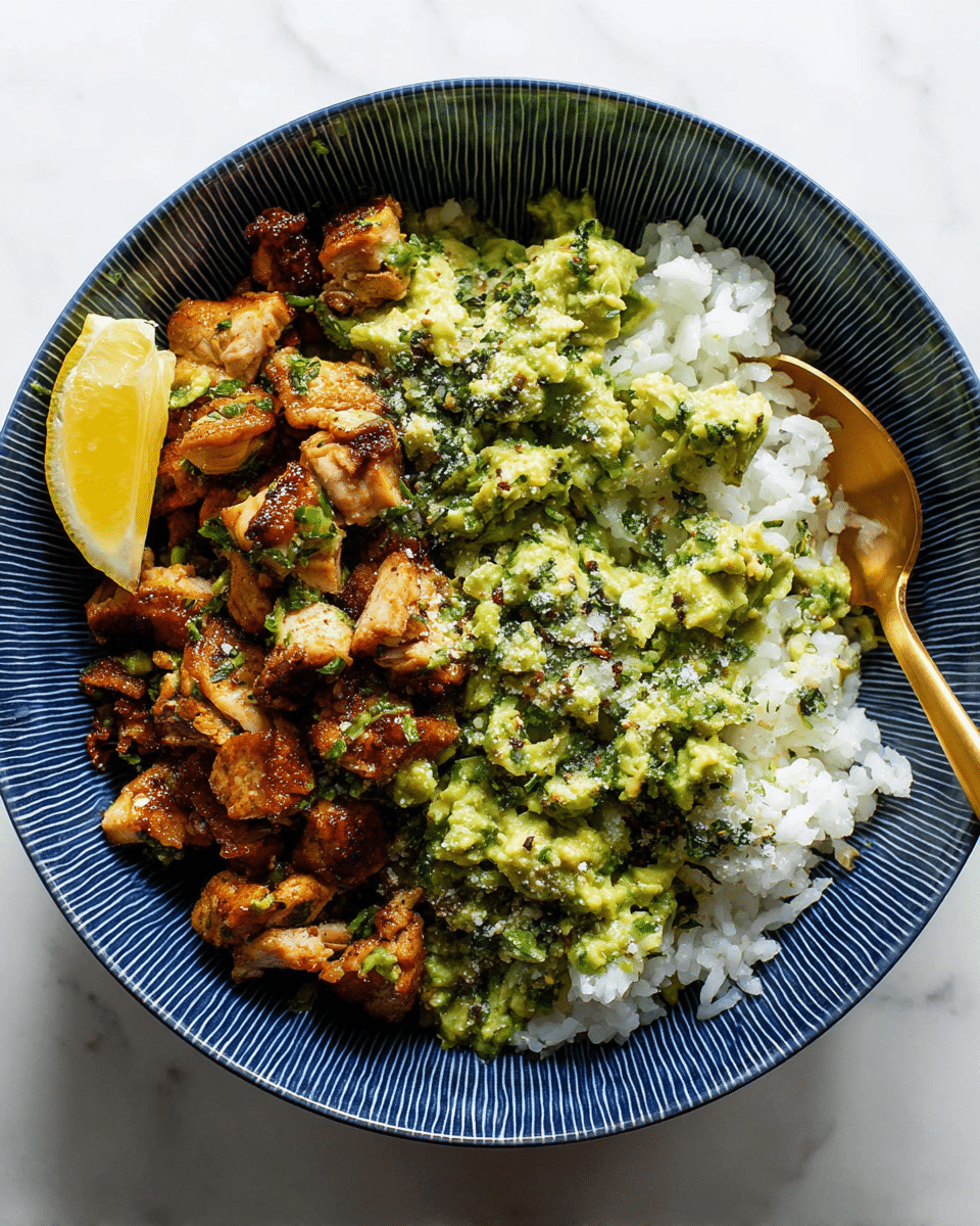 A patterned blue bowl filled with a base layer of white rice on the right side, topped with a layer of roasted, browned chicken pieces scattered across most of the rice, and covered with green mashed avocado mixed with herbs and spices, sprinkled with coarse salt. A slice of yellow lemon rests on the left edge of the bowl, and a golden spoon is placed partially inside the bowl on the right. The bowl is set on a white marbled surface. photo taken with an iphone --ar 4:5 --v 7