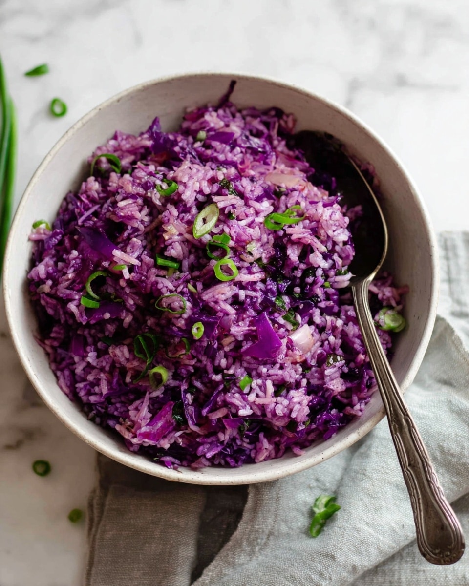 A white bowl filled with a dish of purple rice mixed with finely shredded purple cabbage, giving the rice a rich, vibrant purple color. The rice is topped with small pieces of green chopped scallions scattered evenly on top, adding a fresh contrast. The bowl sits on a soft, grayish cloth on a white marbled surface, with a silver spoon placed inside the bowl on the right side. In the background, there are stacked white bowls and three copper spoons blurred out. Photo taken with an iphone --ar 4:5 --v 7