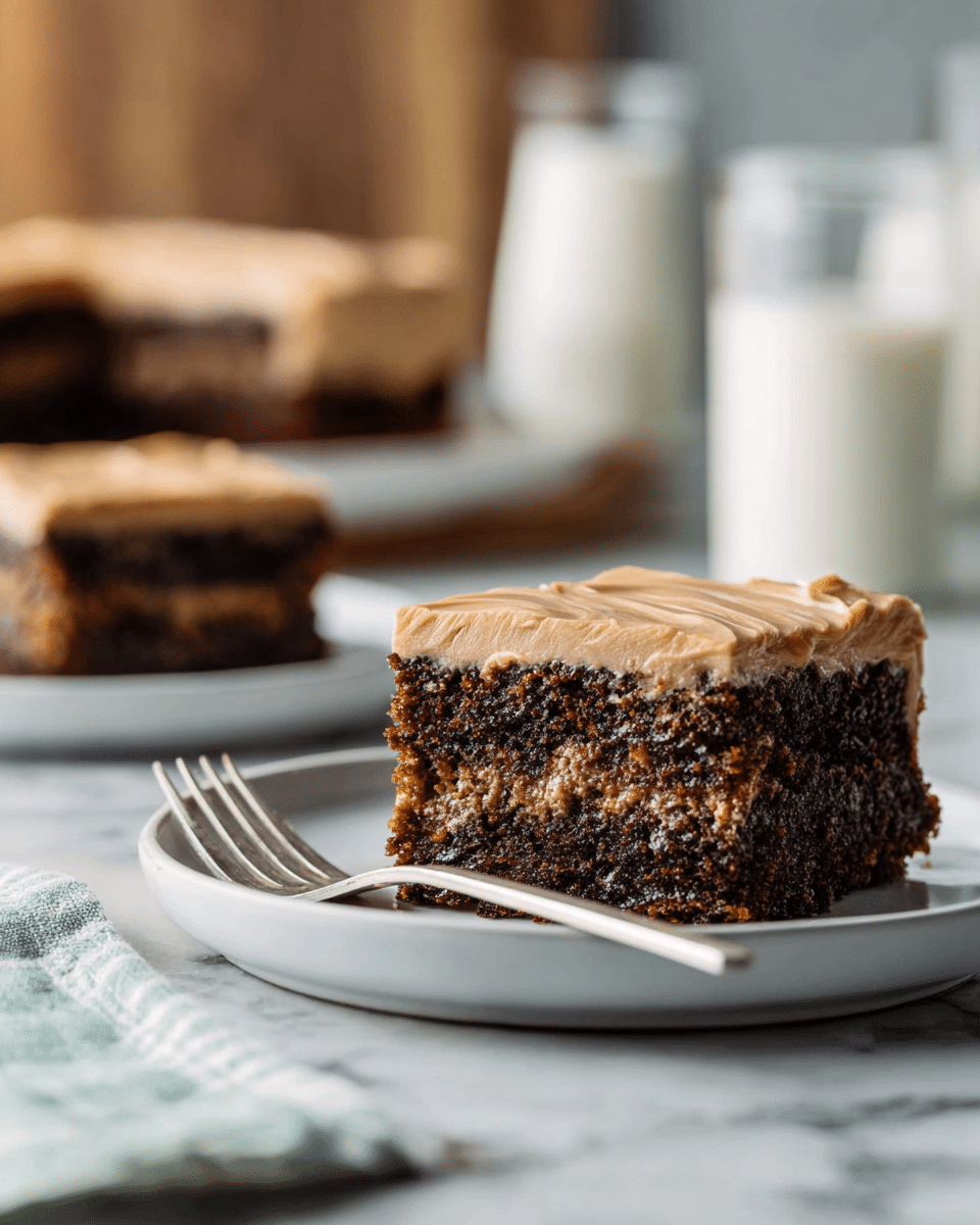 A square piece of dessert with two layers sits on a white plate on a white marbled surface. The bottom layer is a thick, dark brown, moist cake with a slightly crumbly texture, while the top layer is a smooth, light brown frosting that looks creamy and shiny with some gentle swirls across its surface. In the background, there are more similar cake pieces on white plates, slightly blurred, along with a glass and a bottle of milk. Photo taken with an iphone --ar 4:5 --v 7