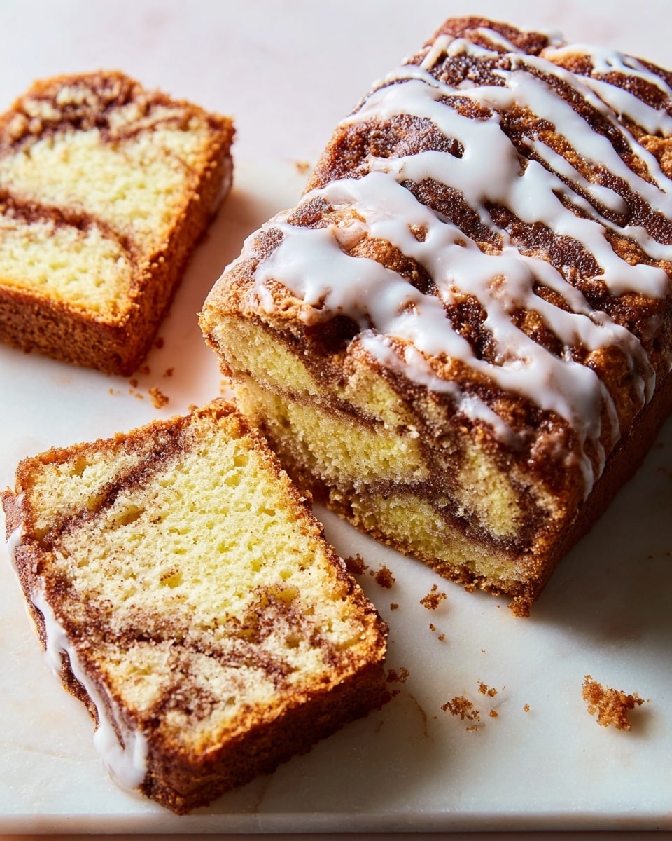 A loaf of cinnamon swirl bread with a dark golden brown crust, drizzled with white glaze on top, sits on a white marbled surface. Two thick slices are cut and lay partly stacked to the left of the loaf, revealing a soft, light yellow inside with a marbled pattern of darker brown cinnamon swirls. The texture looks moist and crumbly, with crumbs scattered nearby. The glaze appears slightly shiny and smooth, running unevenly along the top of the loaf and edges of the slices. photo taken with an iphone --ar 4:5 --v 7