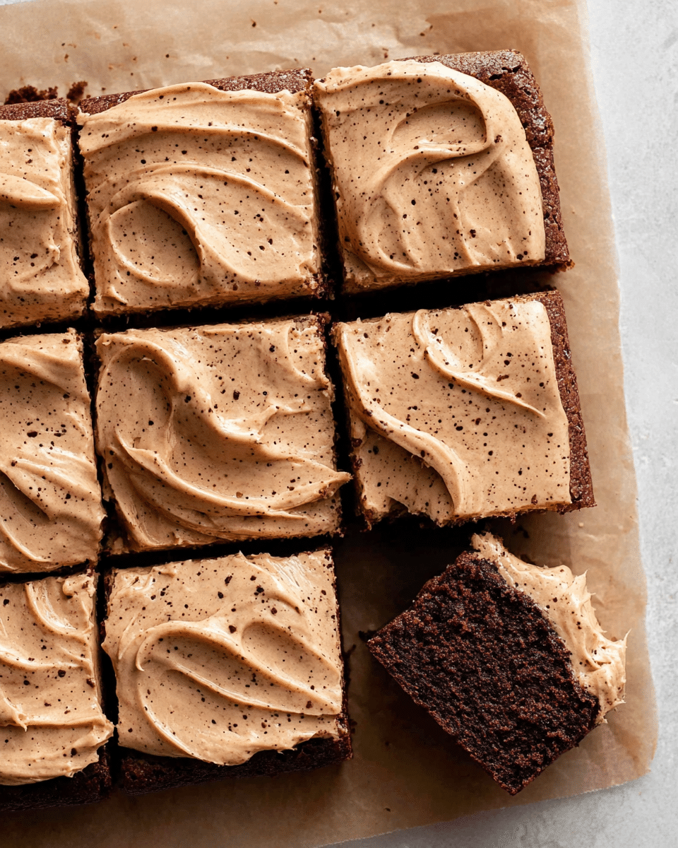 A square piece of chocolate cake on a white plate, with two visible layers: the bottom layer is thick, dark brown, and dense with a moist crumb texture, while the top layer is a smooth, creamy light tan frosting with visible specks and soft swirls. There is a bite taken out of one side of the cake, showing the interior texture. The plate rests on a white marbled surface with a blurred light green cloth in the background and another piece of cake partially visible behind it. Photo taken with an iphone --ar 4:5 --v 7