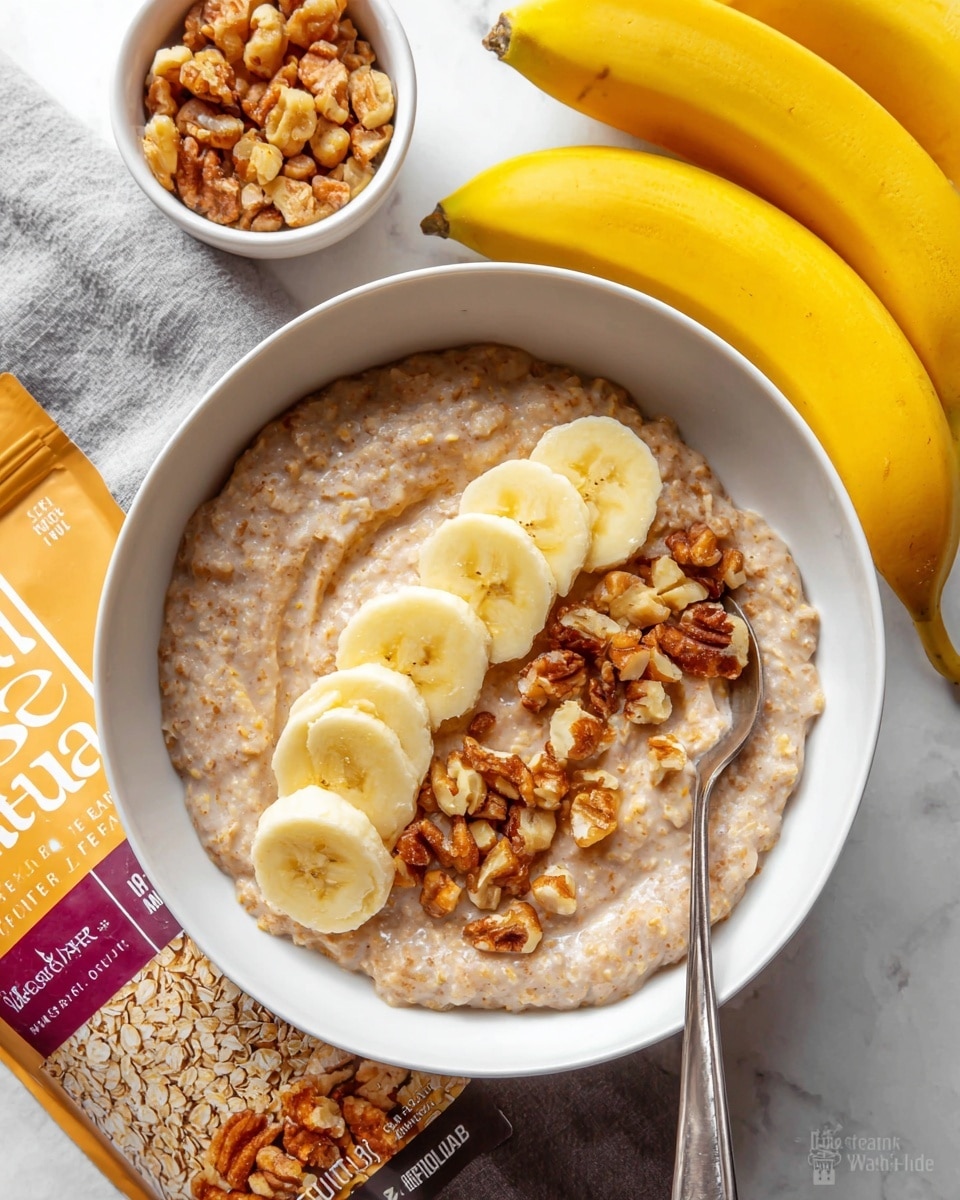 A creamy oatmeal dish fills a white bowl, with a thick, soft texture in light brown color mixed with visible oats. On top, there is a neat row of banana slices showing a pale yellow color, placed from the middle toward one side. Around and over the banana slices, golden brown chopped nuts are scattered, adding crunch and color contrast. A spoon rests inside the bowl, partially submerged in the oatmeal on the right side. The bowl sits on a white marbled surface, alongside a whole yellow banana and a small bowl filled with more chopped nuts. A package of brown sugar replacement lies partially visible next to the bowl, adding context to the scene. photo taken with an iphone --ar 4:5 --v 7