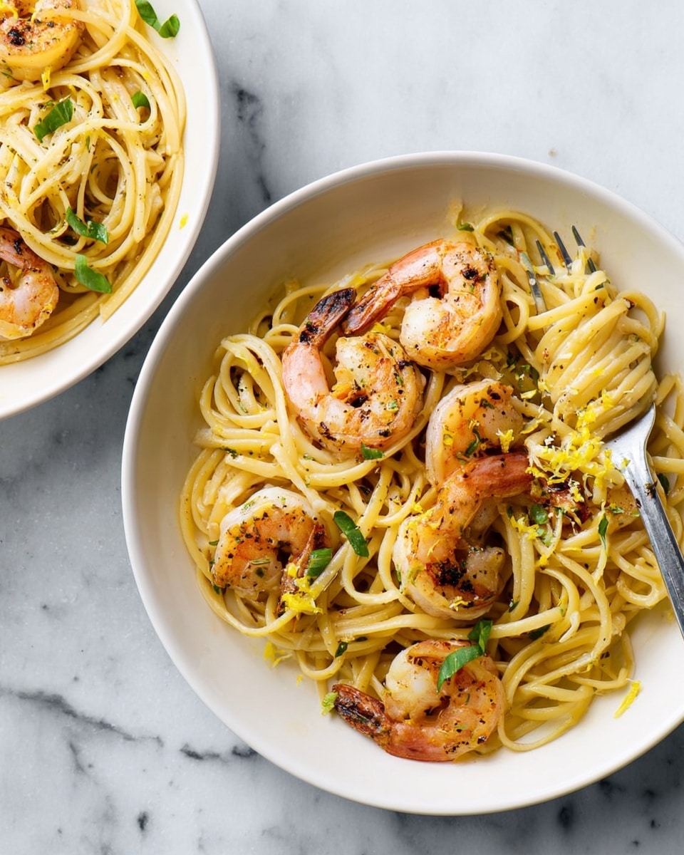 A white bowl filled with spaghetti pasta, mixed with five pink and slightly charred shrimp arranged on top. Light green herb leaves are scattered across the pasta, adding small bursts of color. The spaghetti looks glossy and is seasoned with black pepper and bits of yellow lemon zest. A silver fork rests on the right side inside the bowl. Another white bowl with the same dish is partially visible on the left. The bowls are set on a white marbled surface. photo taken with an iphone --ar 4:5 --v 7