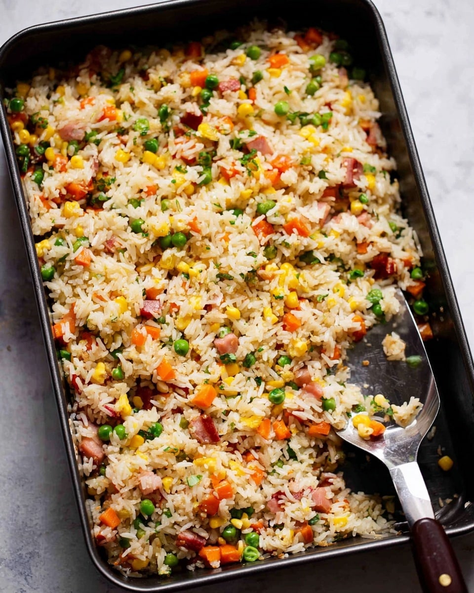 The image shows a close-up of a bowl filled with fried rice. The dish has multiple layers including white rice as the main base, mixed with small pieces of orange carrots, green peas, yellow corn, and diced pink ham. There are also small chopped green onions scattered on top, adding a fresh look. A silver spoon is partially inside the bowl on the right side, resting among the rice and vegetables. The bowl is white, and the background is a white marbled surface. The photo taken with an iphone --ar 4:5 --v 7