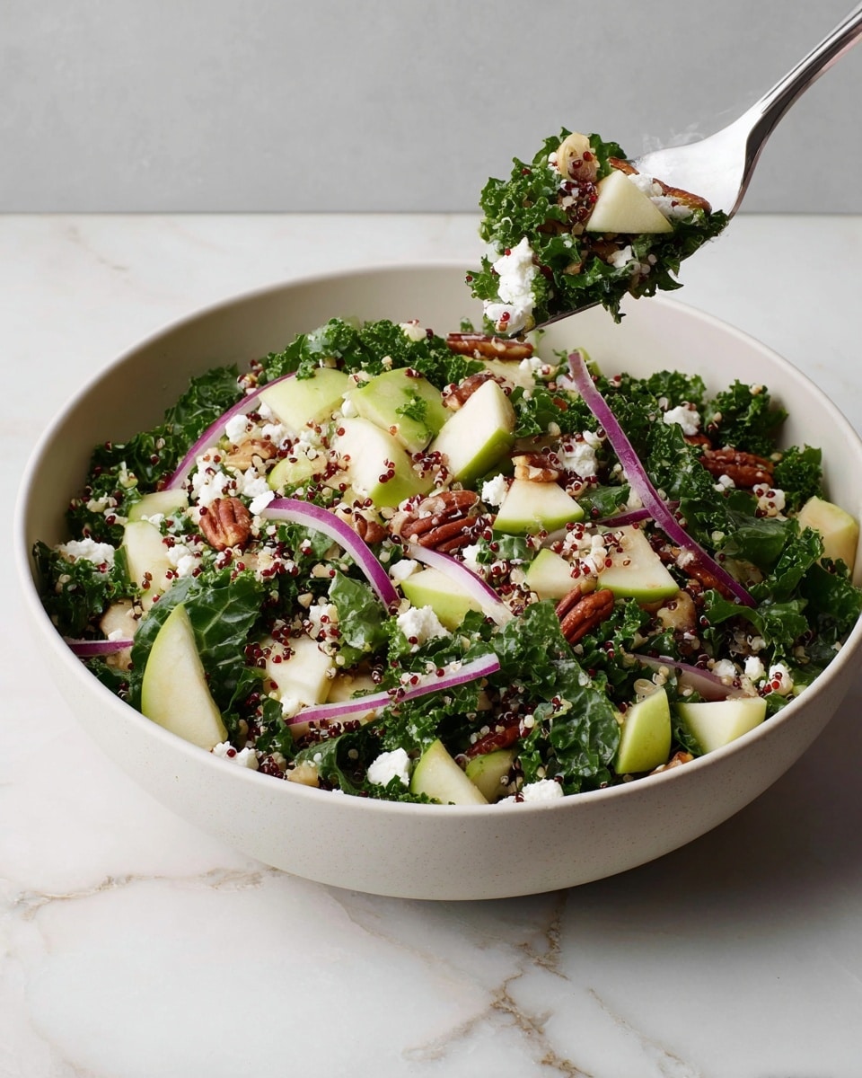 A large white bowl filled with a fresh, colorful salad sits on a white marbled surface. The salad has several layers: first, a base of dark green curly kale leaves; next, chunks of light green apple pieces mixed throughout; then, thin slices of purple onion spread evenly; sprinkled on top are white crumbled cheese pieces and small red quinoa grains; scattered among the layers are reddish-brown pecan nuts adding texture. Above the bowl, a silver fork holds a bite-sized mix of kale, apple, cheese, and a pecan. Photo taken with an iphone --ar 4:5 --v 7