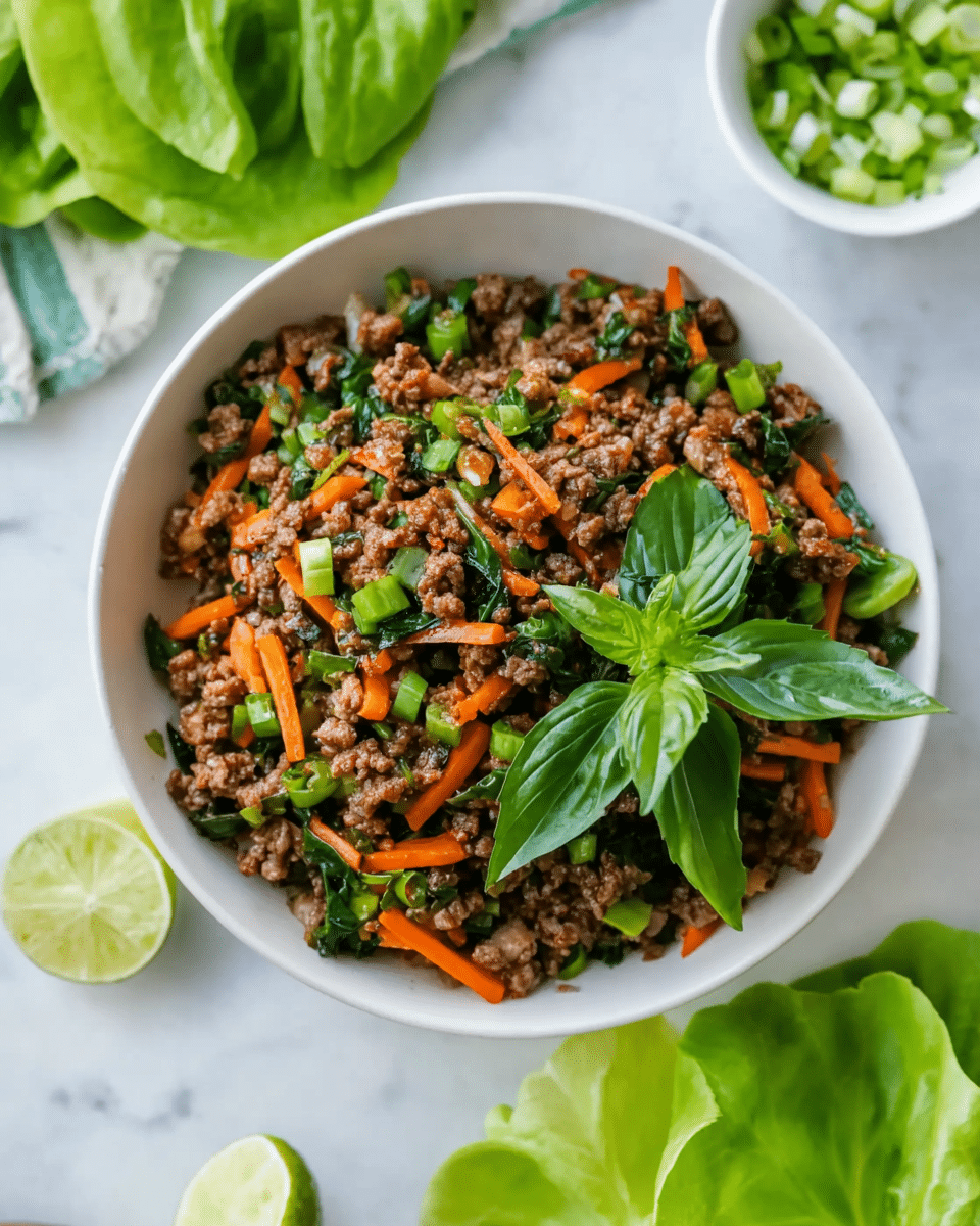 A white bowl filled with a colorful stir-fry sits at the center, consisting of three main layers: the bottom layer is finely minced brown meat, mixed evenly with bright green chopped vegetables and thin orange carrot sticks scattered throughout. On top of this mix, there is a small bunch of fresh, vibrant green basil leaves adding freshness. Surrounding the bowl on a white marbled surface are fresh green lettuce leaves and lime wedges, along with a small white bowl of sliced green onions in the background. The image is bright with natural light, showing the rich textures and colors of the ingredients. Photo taken with an iphone --ar 4:5 --v 7