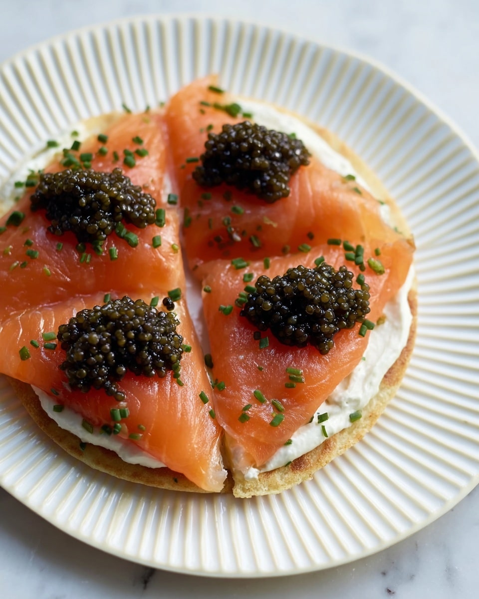 A close-up of a small round pancake with one visible layer of smooth, white cream spread evenly on top. On the cream, four thin slices of bright orange smoked salmon are arranged covering the pancake, each slice folded slightly with a soft, shiny texture. On top of the salmon, there are four small dollops of dark greenish-black caviar, looking glossy and round. The dish is garnished with finely chopped green chives scattered lightly over the salmon and caviar. The pancake is cut into four slices, all placed on a white plate with a subtle ridged pattern, against a white marbled textured background. photo taken with an iphone --ar 4:5 --v 7