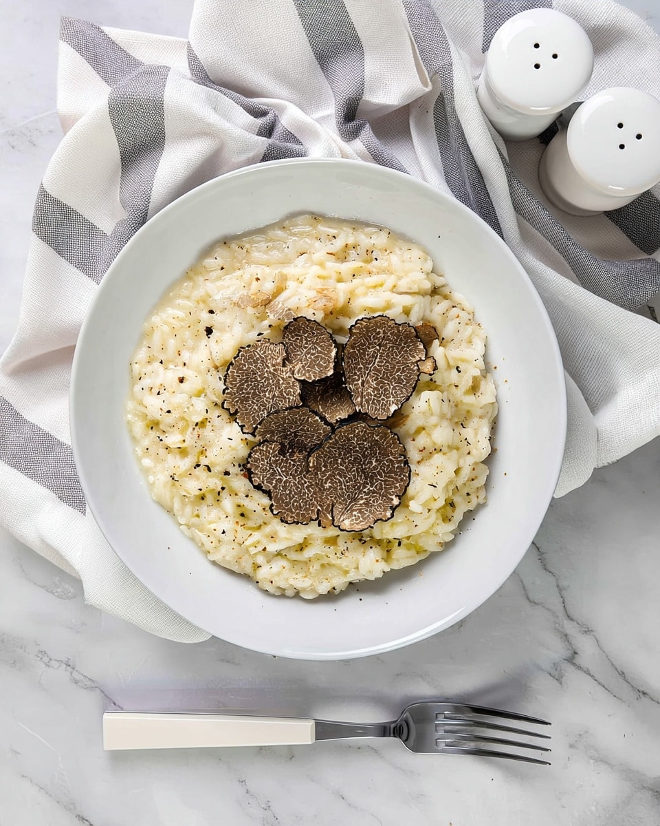 A white bowl filled with creamy risotto, showing a soft, slightly glossy texture in pale cream color; on top, thin slices of light brown truffle with black edges are scattered evenly; small specks of black pepper dot the surface adding contrast; the bowl sits on a white marbled surface next to a fork with a white handle; a white and gray striped cloth and white salt and pepper shakers are near the bowl. photo taken with an iphone --ar 4:5 --v 7