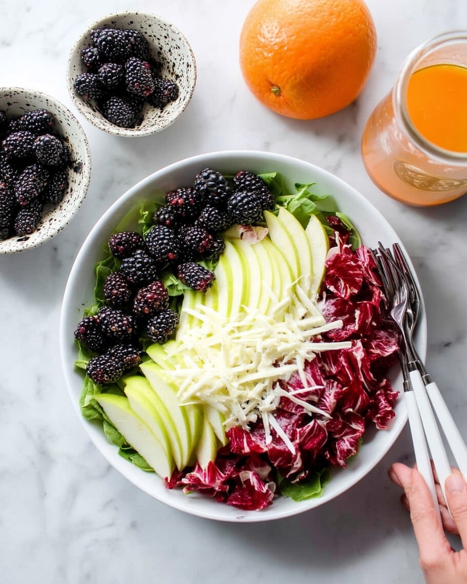 The dish is a fresh salad served on a white round plate with a thin brown rim, placed on a white marbled surface. The salad has a base layer of crisp, curly radicchio leaves in deep red and white tones, mixed with thin slices of pale green apple scattered throughout. On top, there are dark purple blackberries adding a pop of rich color, and several thin flakes of a pale yellow cheese are sprinkled over the salad. To the side of the plate, two gold-colored forks rest gently on the edge, and the whole setup is lit with bright, natural light that highlights the vivid colors and textures. Nearby, small dishes hold additional blackberries and apple slices, with a small glass jar of orange dressing placed next to the plate. Photo taken with an iphone --ar 4:5 --v 7